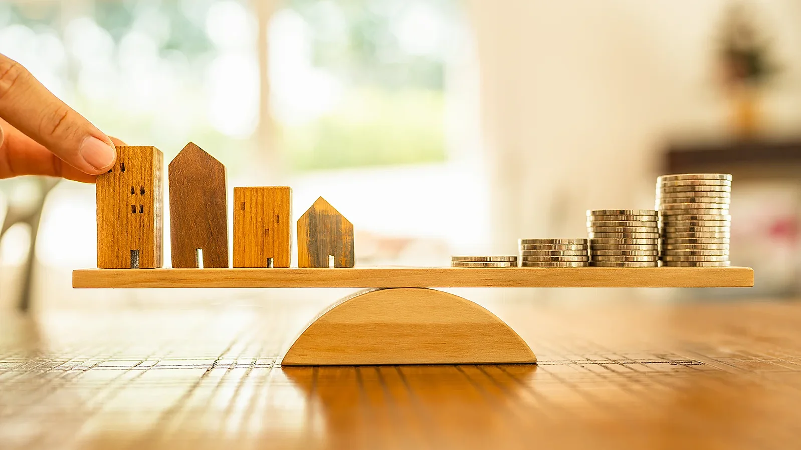 Holzhaus und Münzen stapeln sich mit Waagschale. Geldmanagement, Finanzplan, Zeitwert des Geldes. Immobilien- und Immobilienmakler bieten Hauskonzepte an.